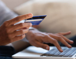 Close up of black girl hold bank credit card and type on laptop, shopping online using computer, buying goods or ordering online, entering bank accounts and details in online banking offer